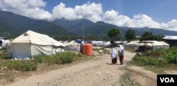 Dua orang siswi Sekolah Dasar Transisi Balaroa berjalan kaki menuju pulang ke tenda tempat tinggal mereka, Sulawesi Tengah, 22 Juli 2019. (Foto: Yoanes Litha/VOA)