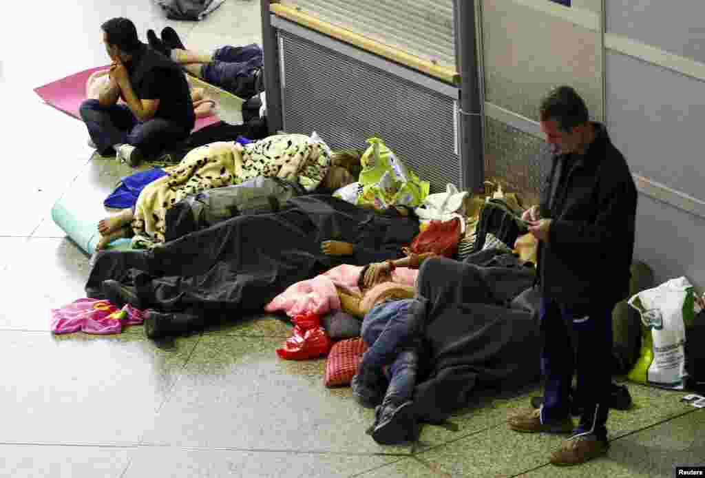 Migrants sleep in the hall of main railway station in Munich. Refugees continued to stream into Germany, favored for its generous welfare system and relatively liberal asylum laws. At Munich&#39;s main train station around 9,200 arrived by early evening.