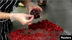 A confectioner arranges a cake shaped like a microscopic view of the coronavirus SARS-CoV-2 at a bakery.