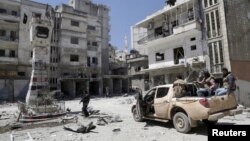FILE - Rebel fighters inspect a site damaged by what activists said was shelling by warplanes loyal to Syria's President Bashar al-Assad in Jisr al-Shughour town, after the rebels took control of the area, April 26, 2015.