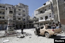 Rebel fighters inspect a site damaged by what activists said was shelling by warplanes loyal to Syria's President Bashar al-Assad in Jisr al-Shughour town, after the rebels took control of the area, April 26, 2015.