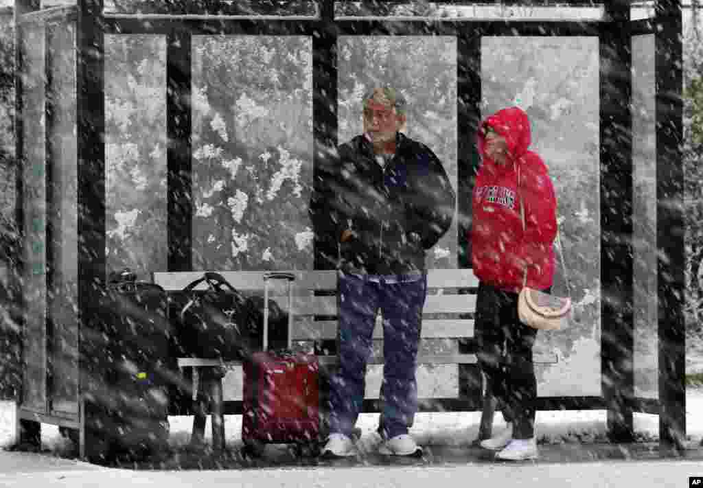 A couple stands in a bus shelter during a snowfall in Dover Township, New Jersey, November 7, 2012, as the region pounded by Superstorm Sandy last week is hit by a Nor'Easter. 