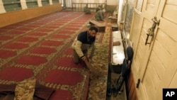 A Kashmiri man clears broken glass and debris inside a mosque after an explosion outside the mosque in Srinagar April 8, 2011.