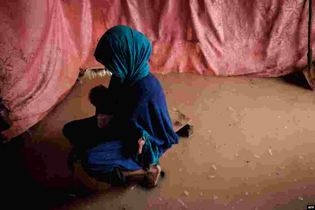 A woman holds her baby in a flooded shelter after a heavy downpour at the Dadaab refugee complex, in the north-east of Kenya, April 17, 2018.