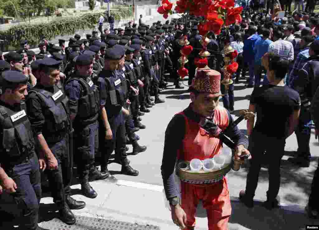 A Palestinian coffee vendor walks past rows of police officers during U.S. President Barack Obama's visit in the West Bank city of Ramallah March 21, 2013. 
