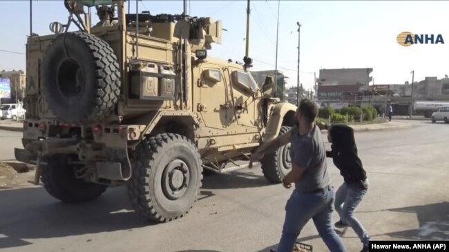 Residentes kurdos de Qamishli, en el noreste de Siria, lanzan patatas a blindados estadounidenses que abandonan el área. (Foto la agencia kurda Hawar News, ANHA, publicada por AP)