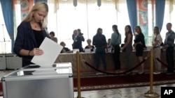 A woman casts her ballot as voters line up at a polling station during parliamentary elections in Minsk, Belarus, Sept. 11, 2016.