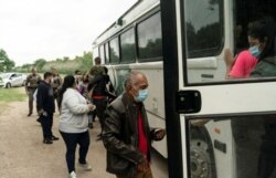 میکسیکو کے ایک سرحدی قصبے سے پناہ گزین بس میں سوار ہو رہے ہیں۔ 27 مئی 2021