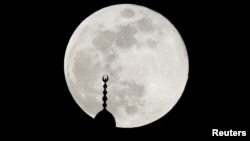 Bulan purnama menyinari menara masjid di Amman, Yordania, 7 Mei 2020. (Foto: Reuters)