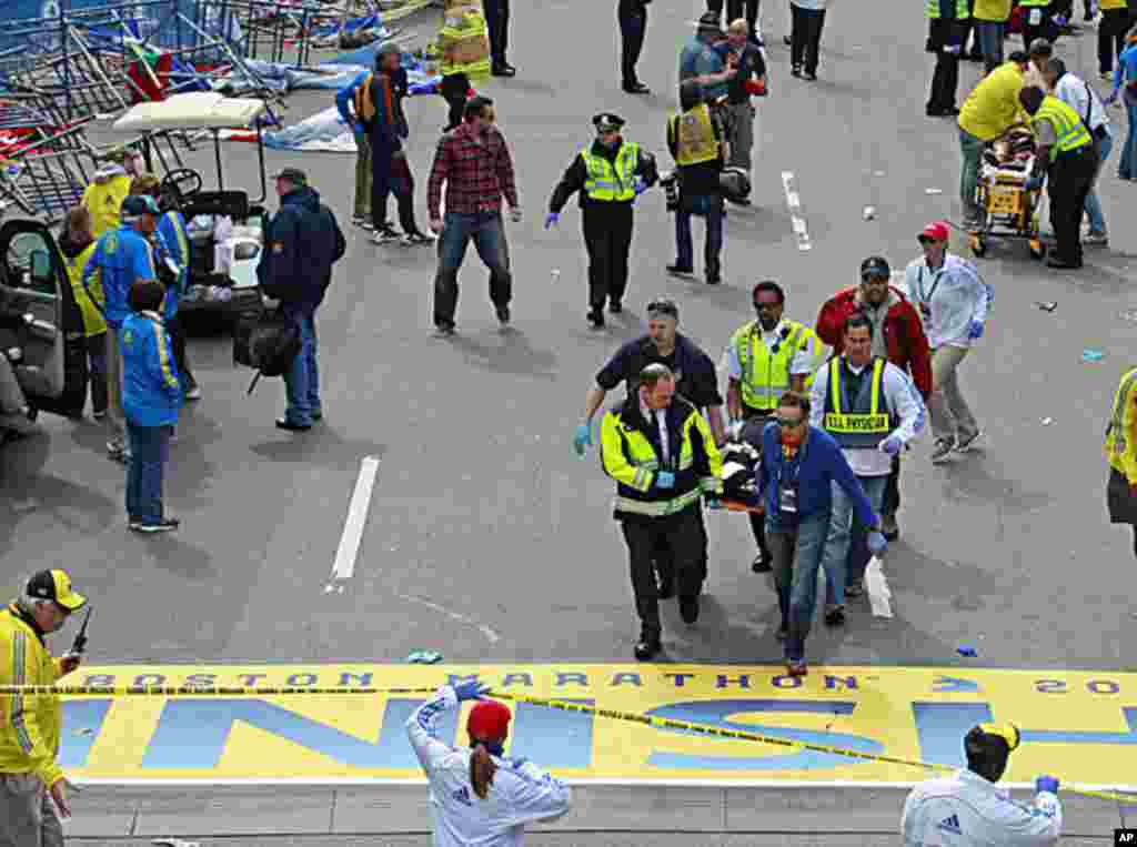 Para petugas medis membawa korban luka ledakan bom pada Marathon Boston (15/4). (AP/Charles Krupa) 