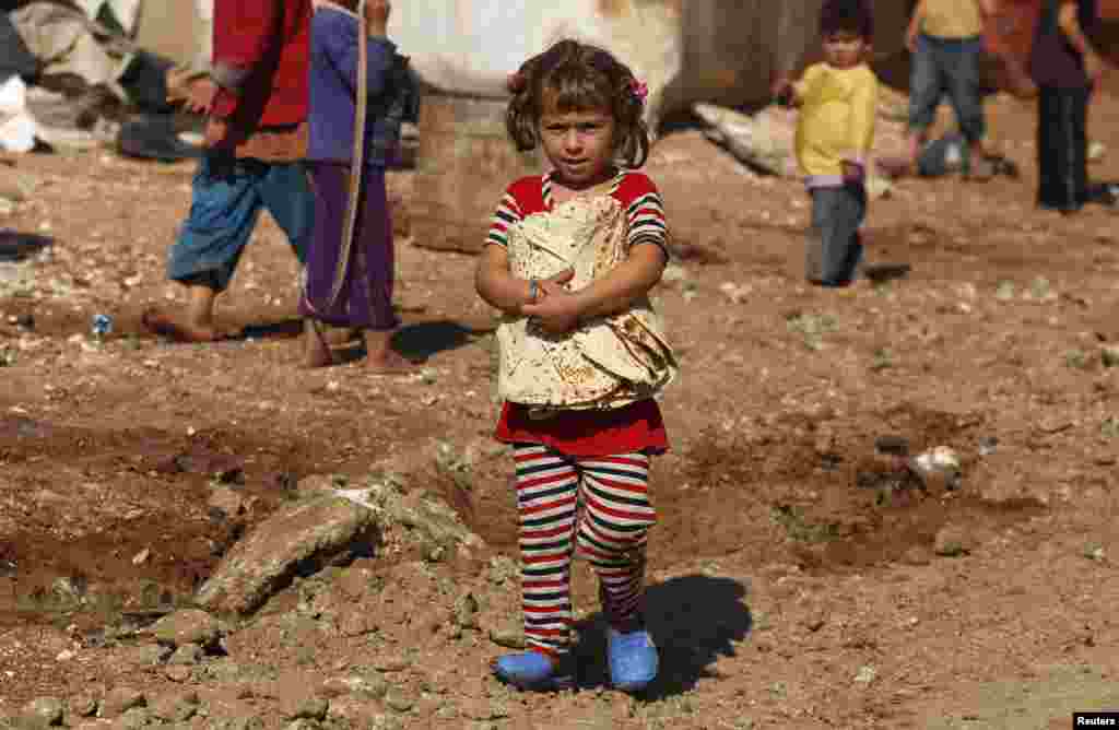 A girl carries bread outside the tents in the Bab Al-Salam refugee camp in Azaz, Oct. 27, 2014.