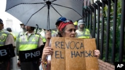 FILE - A woman holds a sign with a message that in reads in Spanish "Revoke hunger" during a protest march in Caracas, Venezuela, July 27, 2016.