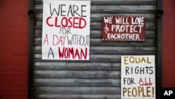 FILE - Signs are posted in solidarity with "A Day Without a Woman" in Philadelphia, March 8, 2017. Organizers were calling on women to stay home from work and not spend money in stores or online to show their impact on American society. 
