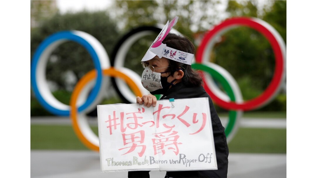 Pengunjuk rasa anti-Olimpiade membawa plakat di depan monumen cincin Olimpiade di luar markas besar Komite Olimpiade Jepang di tengah pandemi COVID-19, di Tokyo, Jepang, 18 Mei 2021. (REUTERS / Issei Kato)