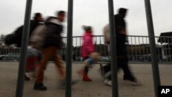 Refugees and migrants are seen walking behind a fence at the border between Slovenia and Austria at Spielfeld, Austria, Feb. 16, 2016. 