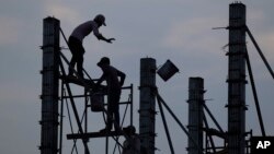 FILE - Workers on scaffolding are silhouetted at a construction site near Phnom Penh, Cambodia.