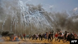 Palestinians run for cover from tear gas during clashes with Israeli security forces near the border between Israel and the Gaza Strip, east of Jabalia, May 14, 2018, as Palestinians protest over the inauguration of the U.S. embassy following its controversial move to Jerusalem.