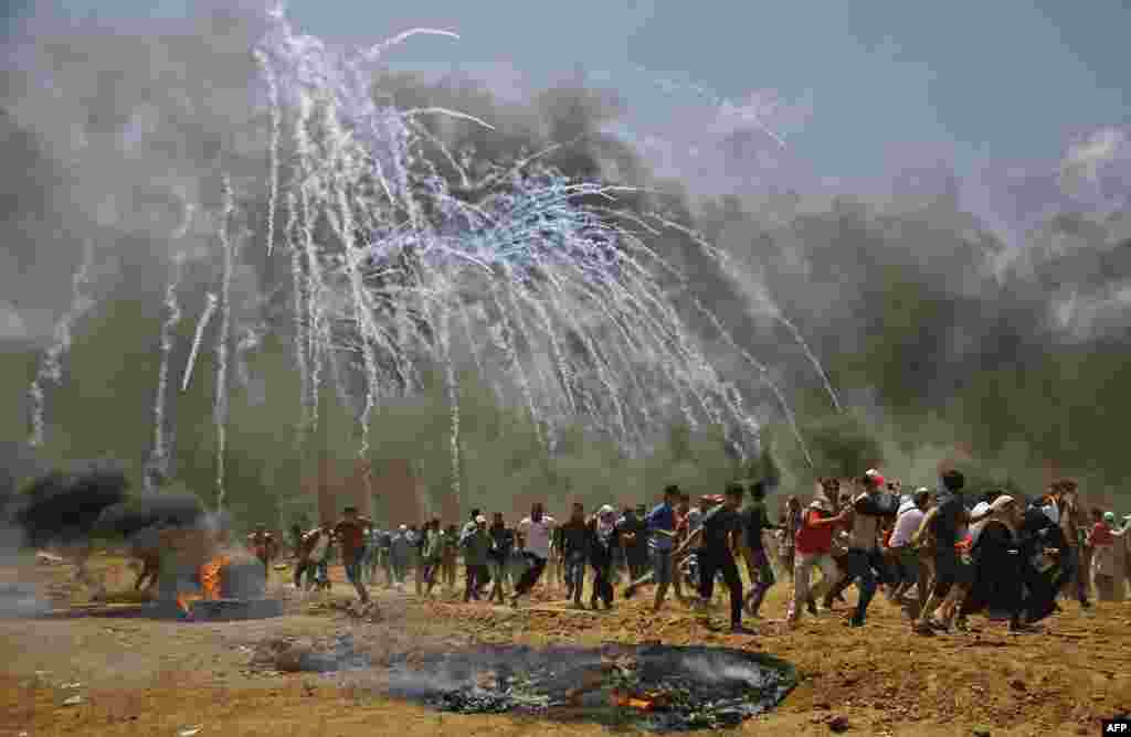 Palestinians run for cover from tear gas during clashes with Israeli security forces near the border between Israel and the Gaza Strip, east of Jabalia, May 14, 2018, as Palestinians protest over the inauguration of the U.S. embassy following its controversial move to Jerusalem.