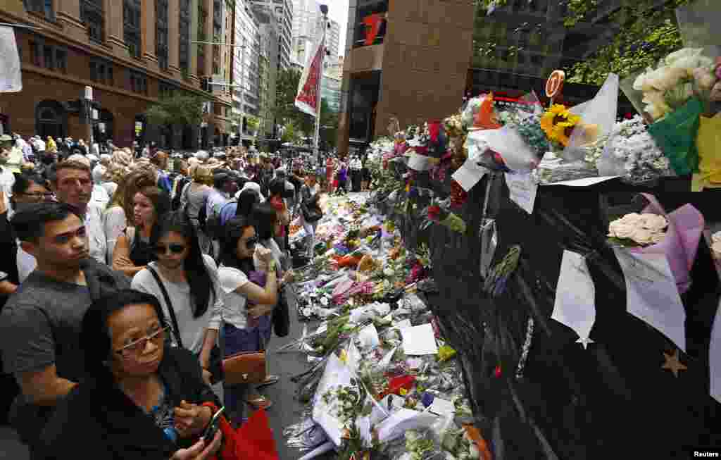 Masyarakat di situs memorial dekat kafe Lindt di distrik bisnis Sydney, Australia, tempat warga terus memberikan bunga tanda penghormatan, Kamis (18/12). ​