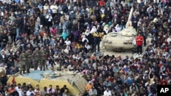 Anti-government protesters, and Egyptian Army soldiers on top of their vehicles, make traditional Muslim Friday prayers at the continuing demonstration in Tahrir Square in downtown Cairo, February 11, 2011