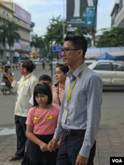 Former Radio Free Asia journalist Yeang Sothearin holds his daughter's hands in front of the Phnom Penh Municipal Court Friday, Oct. 3, 2019. (Aun Chhengpor/VOA Khmer)