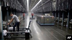 Workers exchange spools of thread as a robot picks up thread made from recycled plastic bottles at the Repreve Bottle Processing Center in Yadkinville, N.C., Oct. 21, 2016. America has lost more than 7 million factory jobs since manufacturing employment peaked in 1979. Yet American factory production, minus raw materials and some other costs, more than doubled over the same span to $1.91 trillion last year, according to the Commerce Department, which uses 2009 dollars to adjust for inflation. 