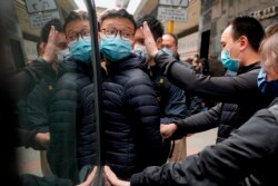 Editor of Stand News Patrick Lam, center, is escorted by police officers into a van after they searched evidence at his office in Hong Kong, Dec. 29, 2021. (AP)