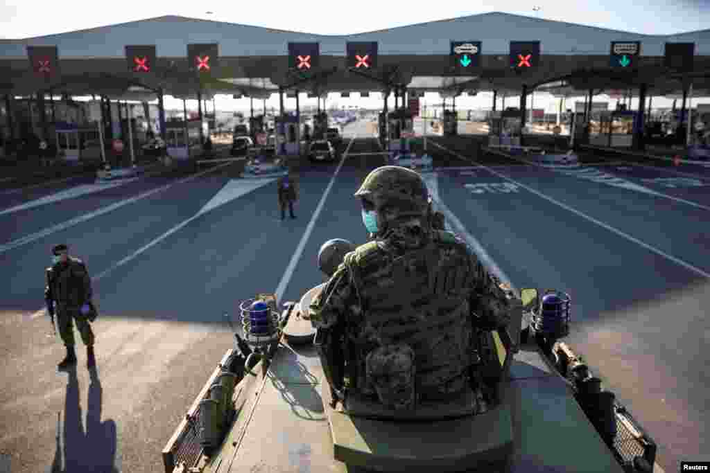 A Serbian army soldier sits on top of armored personal carrier at the Serbia&#39;s Batrovci border crossing with Croatia&#39;s Bajakovo, as the number of coronavirus cases grow around the world, March 18, 2020.