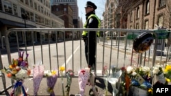 Boston police officer stands guard at a memorial site at Boylston and Arlington streets along the course of the Boston Marathon on April 16, 2013, a few blocks from where two explosions struck near the finish line.