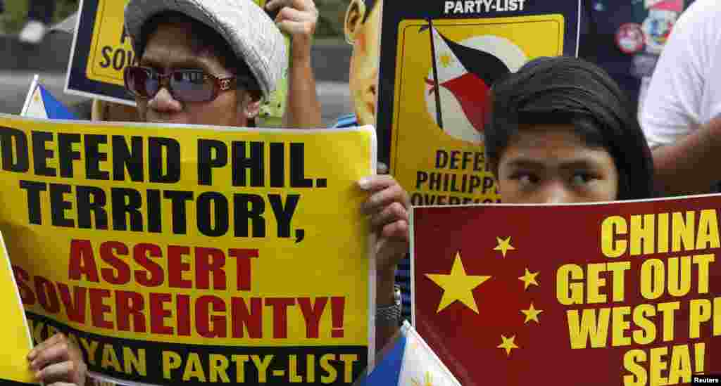 Protesters display placards as they march to the Chinese consulate office in Manila, June 12, 2014. 