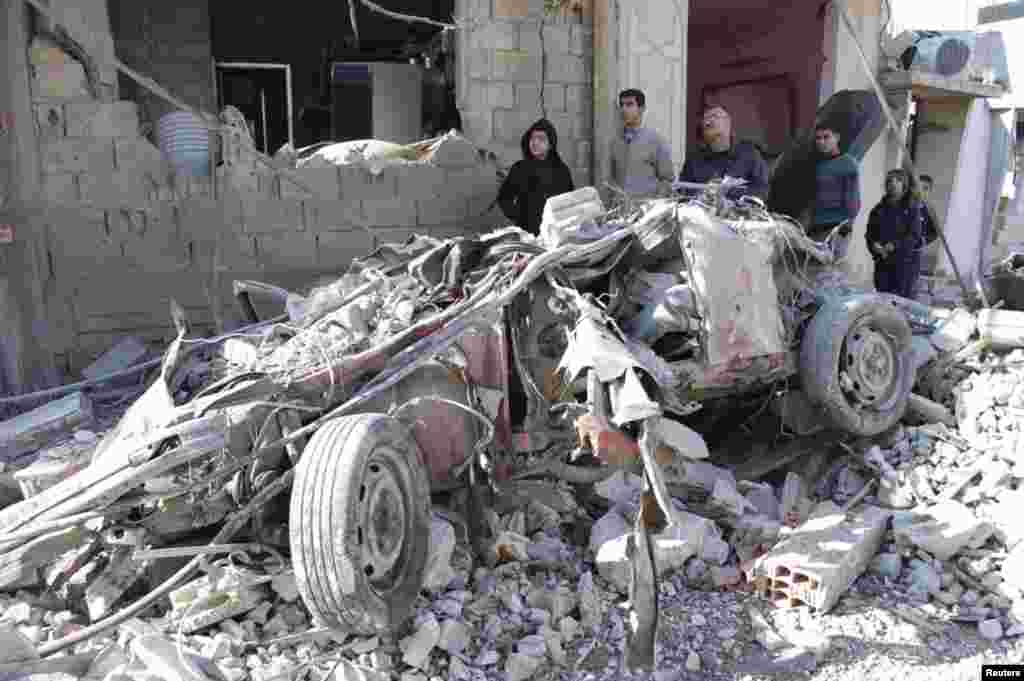 The remains of a car destroyed by a suicide bomb near the&nbsp;front of a damaged building in Al-Kafat, Jan. 9, 2014.