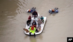 Evacuees make their way though floodwaters near the Addicks Reservoir as floodwaters from Tropical Storm Harvey rise, Aug. 29, 2017, in Houston.