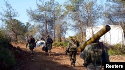 FILE - A rebel fighter carries an anti-tank weapon (R) as he heads with his fellow fighters towards their positions in the Armenian Christian town of Kasab, Apr. 23, 2014. 