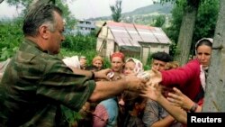 Prvostepeni ratni osuđenik Ratko Mladić deli hranu bošnjačkoj populaciji u Potočarima; 13. jul 1995.