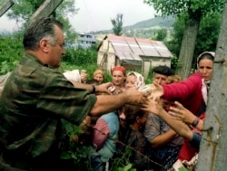 Bosnia and Herzegovina, Bosnian Serb army Commander General Ratko Mladic hands out cans of bevarages to Bosnian Moslems, refugees from Srebrenica, as the wait to be transported from eastern Bosnian village of Potocari