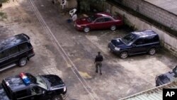 FILE - An unidentified policeman provides security inside the compound of a wealthy Nigerian man, with cars parked ready to provide armed convoys, and the compound protected by high walls and barbed wire in Port Harcourt, Nigeria, July 27, 2007. 