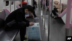 乘坐武漢地鐵的乘客在看手機。（2020年4月1日）