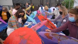 AFS exchange students and volunteers paint colors on paper umbrellas at a demonstrated workshop during a day-long tour of Thai Town hosted by the Thai Town Council Of Los Angeles in Los Angeles, CA.