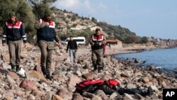 土耳其軍警站在恰納卡萊省艾瓦哲克城附近海灘上的一名移屍體旁。（2016年1月30日）