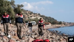 터키 경찰이 30일 에게해 인근의 해변마을에서 사망한 이민자 시신 옆에 서 있다.