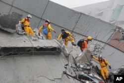 Rescue workers search a collapsed building from an early morning earthquake in Tainan, Taiwan, Saturday, Feb. 6, 2016.