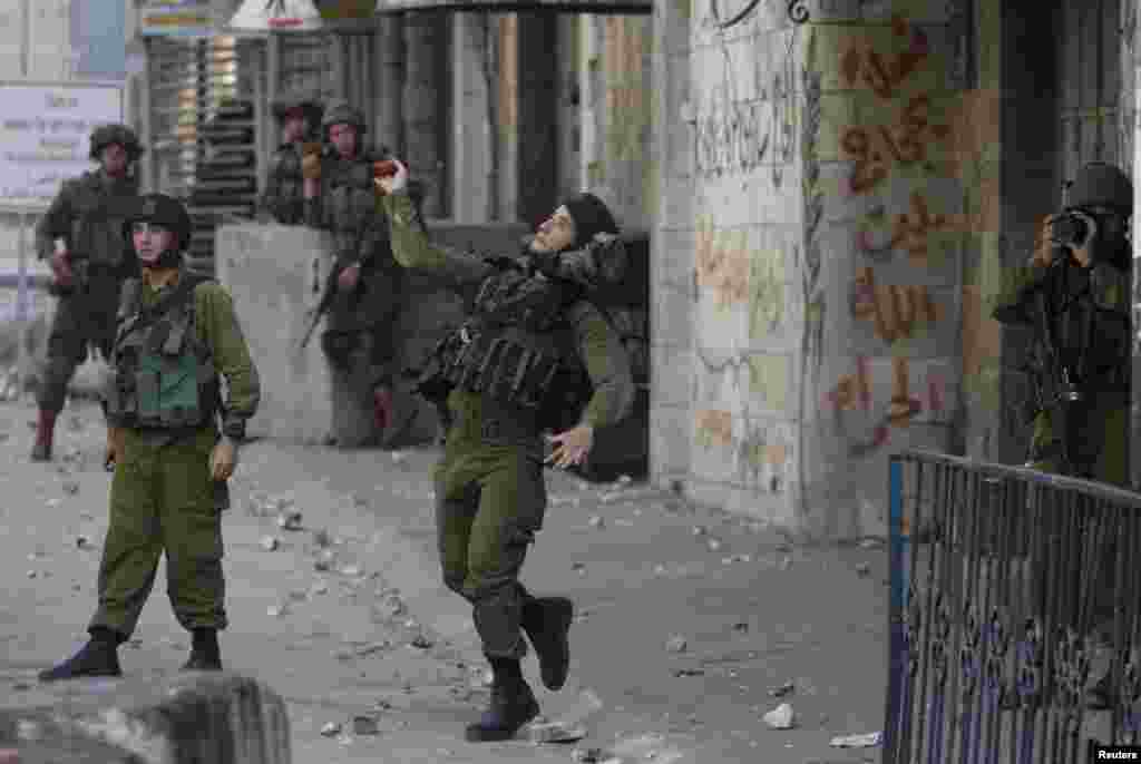 An Israeli army soldier throws a sound grenade at Palestinians during clashes following the funeral of 19-year-old Palestinian student Hadeel al-Hashlamun in the occupied West Bank city of Hebron. The Israeli military said troops shot al-Hashlamun as she tried to stab a soldier. But relatives of al-Hashlamun denied the Israeli report saying she was executed. In a picture posted on Facebook, a soldier could be seen aiming his rifle at a woman said to be Hashlamun, standing a short distance away. She was completely covered in a black robe.