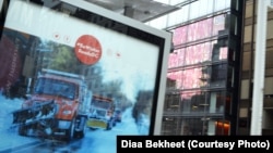 A billboard screen on a sidewalk shows a reflection of sweeping trucks removing snow in Washington, D.C. (Photo: Diaa Bekheet)