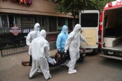 Izhaar Hussain Shaikh, kiri, seorang pengemudi ambulans yang bekerja untuk HelpNow, menjemput seorang pasien COVID-19 dari rumahnya di Mumbai, India, 28 Mei 2020. (Foto: AP)