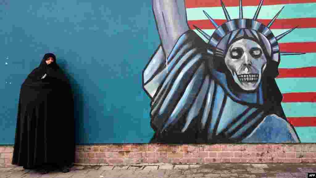 An Iranian woman stands in front of the painted wall of the former U.S. embassy in Tehran where a demonstration took place marking the anniversary of 35 years after Islamist students stormed the embassy compound, then holding 52 American diplomats hostage for 444 days. 