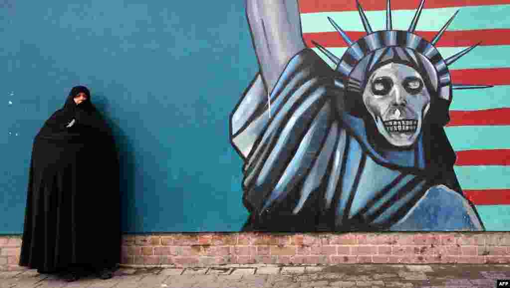 An Iranian woman stands in front of the painted wall of the former U.S. embassy in Tehran where a demonstration took place marking the anniversary of 35 years after Islamist students stormed the embassy compound, then holding 52 American diplomats hostage for 444 days.