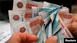 FILE - An employee counts Russian rouble banknotes at a shop in Krasnoyarsk, Dec. 26, 2014. 