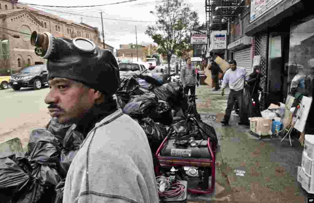 Raymond Palermo, left, wears a protective mask as he helps to remove debris from his cousin's electronics store in Brooklyn, NY, Oct 31, 2012