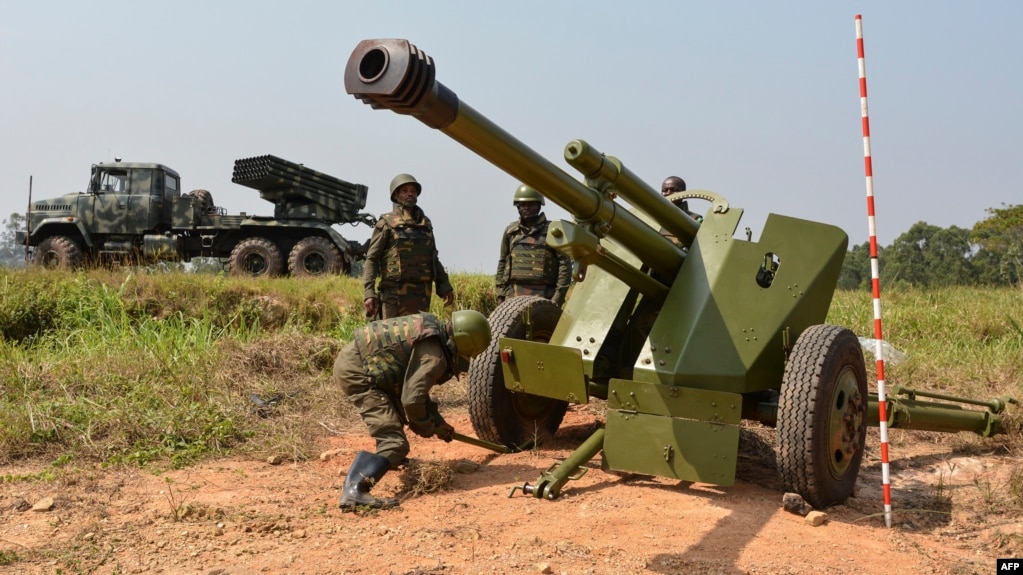 Des soldats des forces armées de la République démocratique du Congo (FARDC) installent une pièce d'artillerie mobile (Front) à côté d'un lance-roquettes multiples mobile à Matombo, à 35 km au nord de Beni, au Nord Kivu, le 13 janvier 2018.