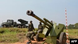 Des soldats des forces armées de la République démocratique du Congo (FARDC) installent une pièce d'artillerie mobile à côté d'un lance-roquettes multiples mobile à Matombo, à 35 km au nord de Beni, au Nord Kivu, le 13 janvier 2018.